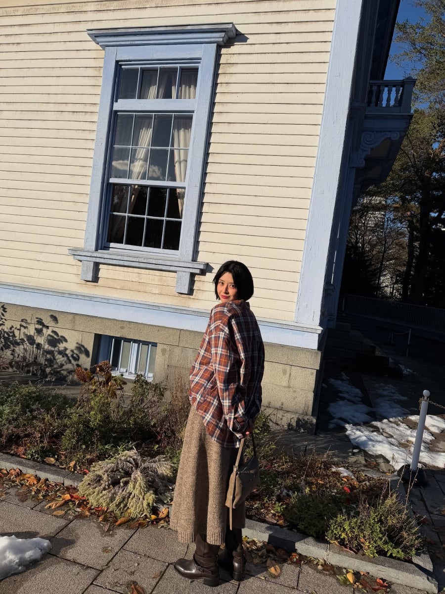 Trong bộ cánh tông nâu làm chủ đạo, Kwon Nara ghi điểm nhờ cách phối hài hòa giữa áo sơ mi kẻ và chân váy len mềm mại.